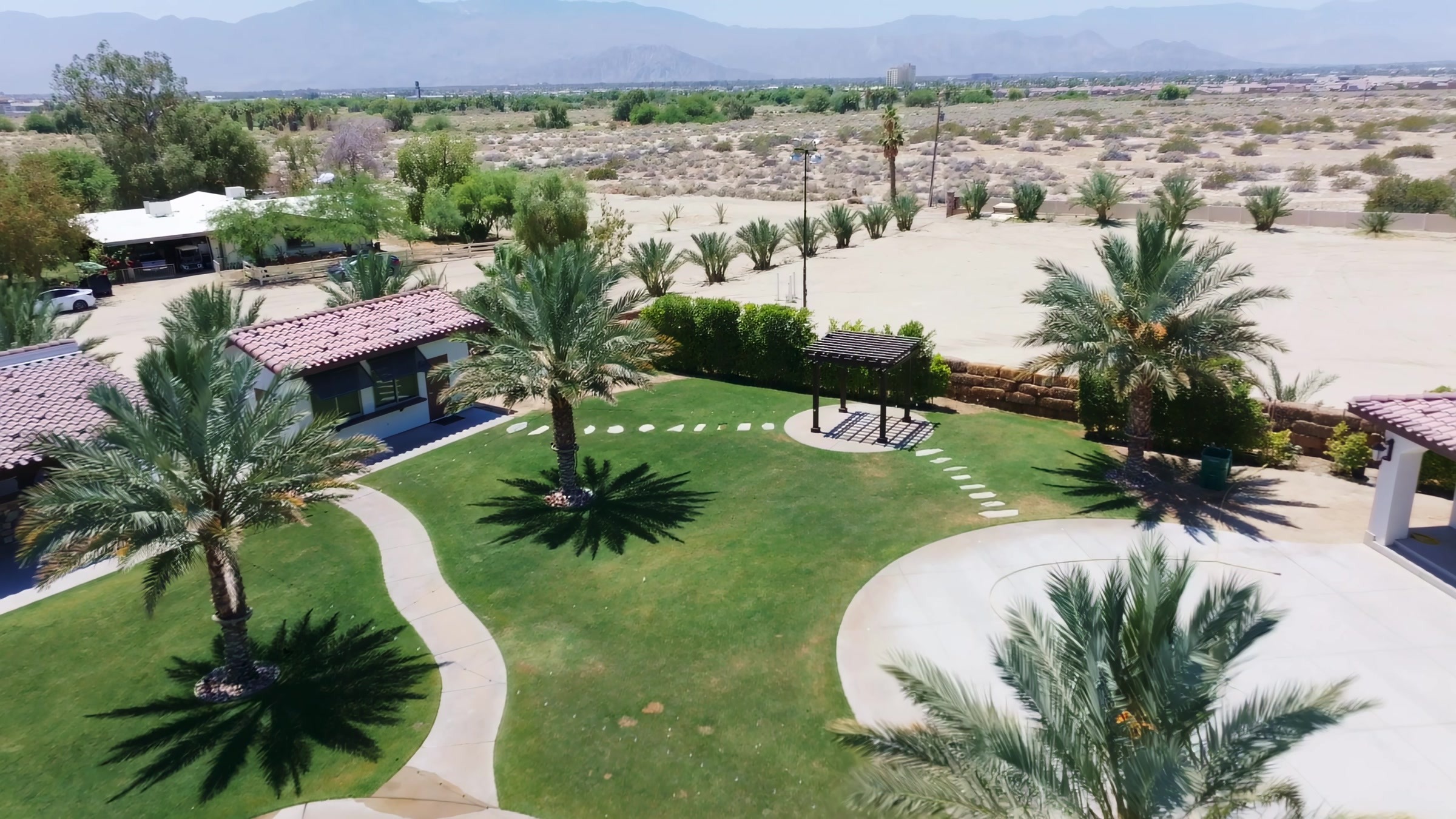 Angled aerial of Rancho Escondido ceremony courtyard with arch and palm trees in Indio, California.