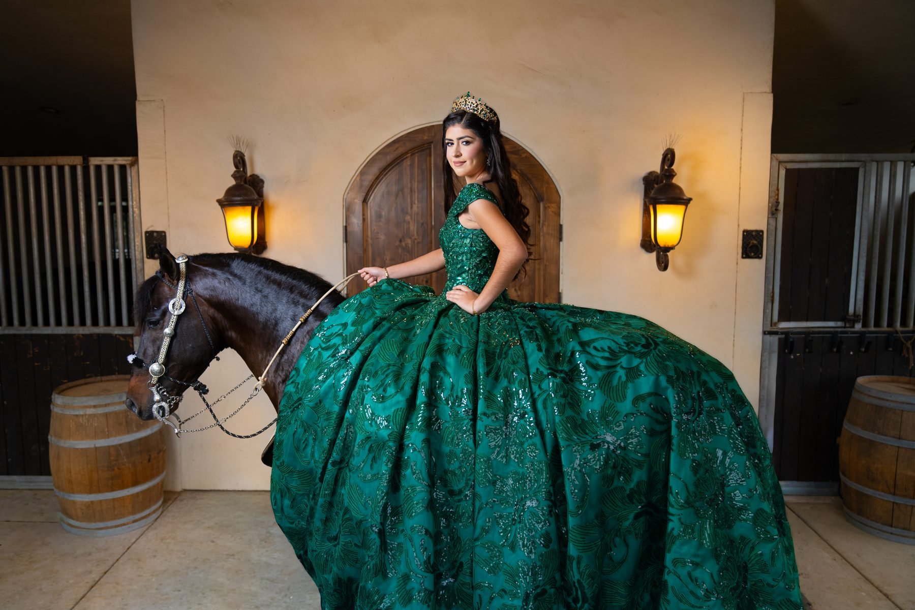 Quinceañera in emerald ball gown beside a horse at the Rancho Escondido stables in Indio, California.