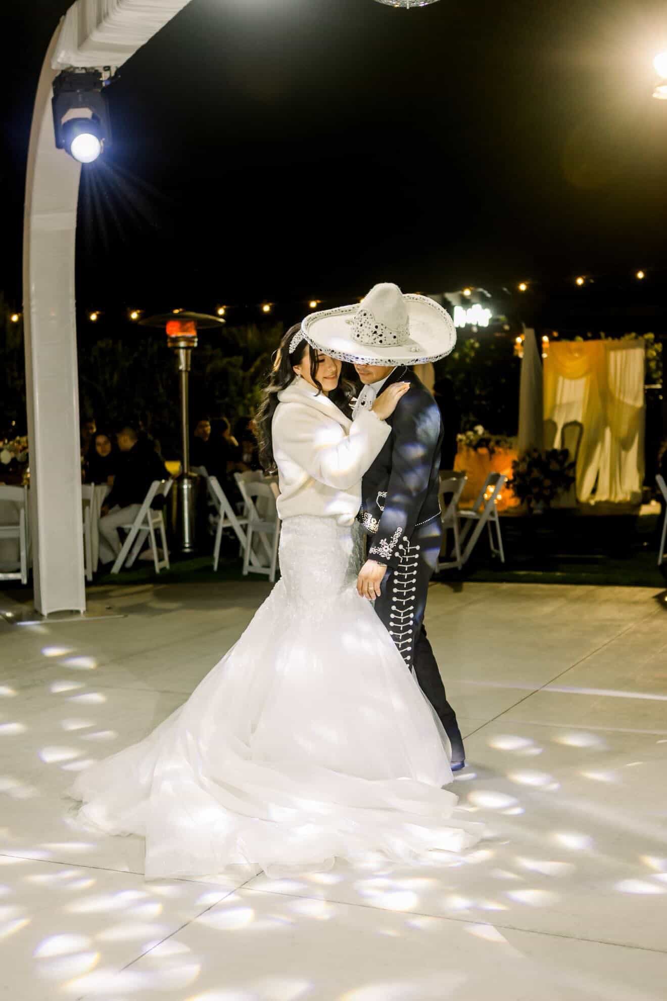 Bride and groom in charro attire sharing first dance on the lit dance floor at Rancho Escondido wedding.